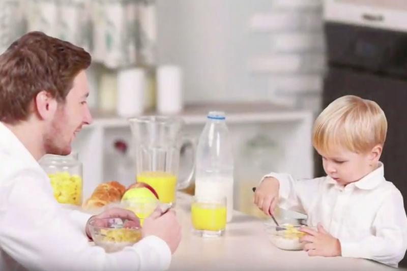 Father and young song eating breakfast at a table together.