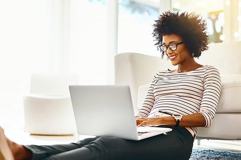 African American woman with glasses working on her laptop.