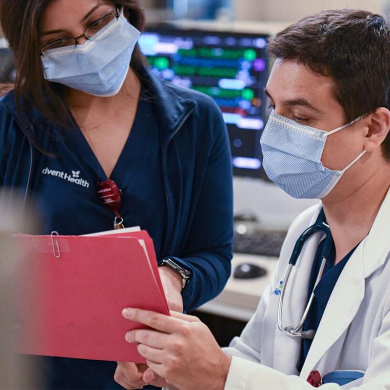 Two doctors in masks reviewing patient charts.