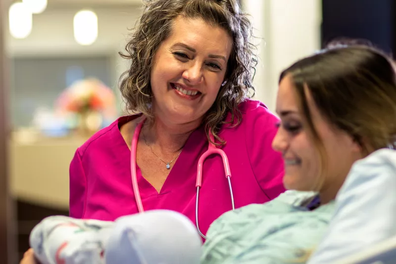 Texas Health Huguley nurse looking over patient and her new baby
