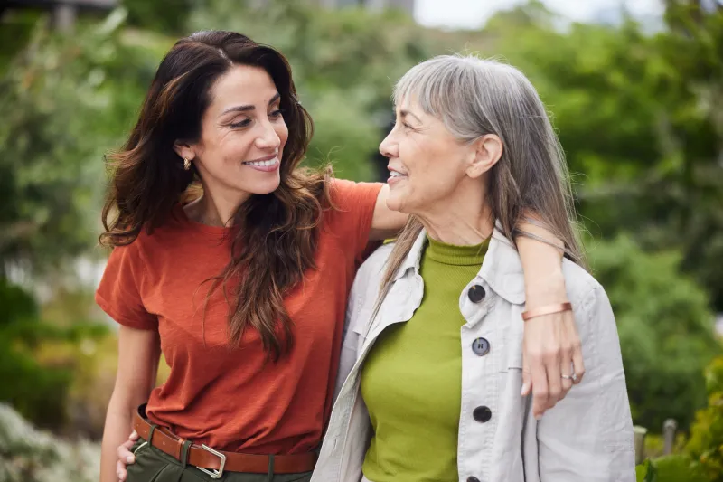 Mother and daughter hugging, walking through their garden