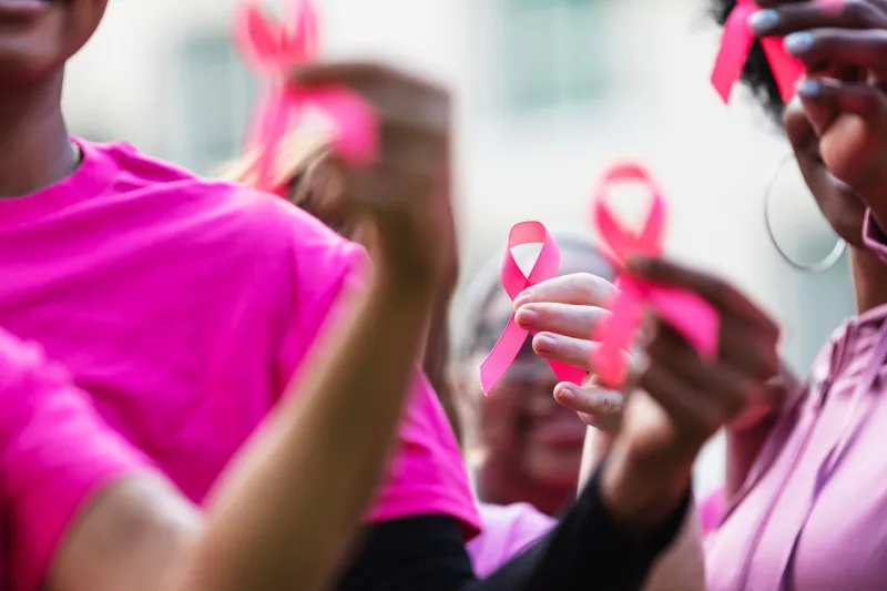 Women wearing pink holding their pink ribbons together