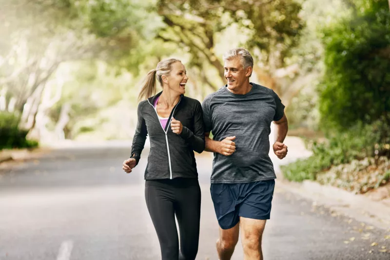 Older couple jogging on a trail through the trees