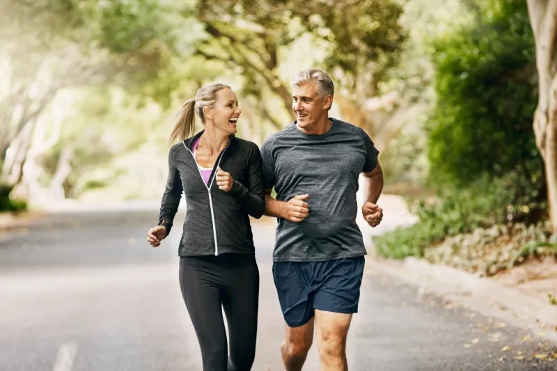 Older couple jogging on a trail through the trees