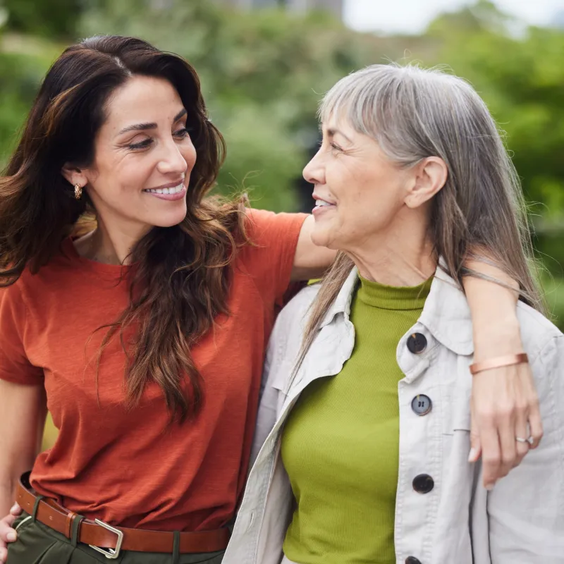 Mother and daughter hugging, walking through their garden