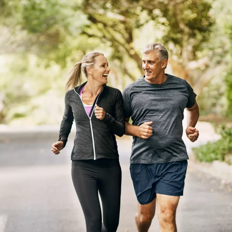 Older couple jogging on a trail through the trees