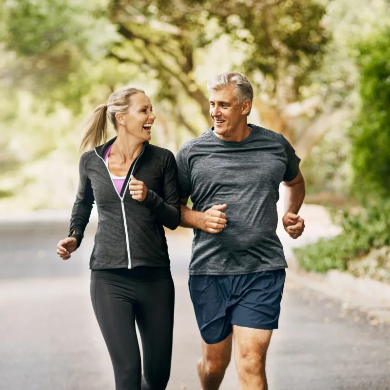 Older couple jogging on a trail through the trees