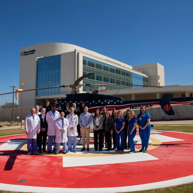 Texas Health Huguley team members and EMS workers standing in front of a helicopter in front of the THH ED