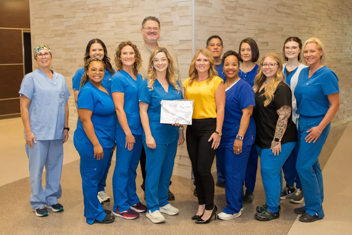 Group of team members posing together to display an award